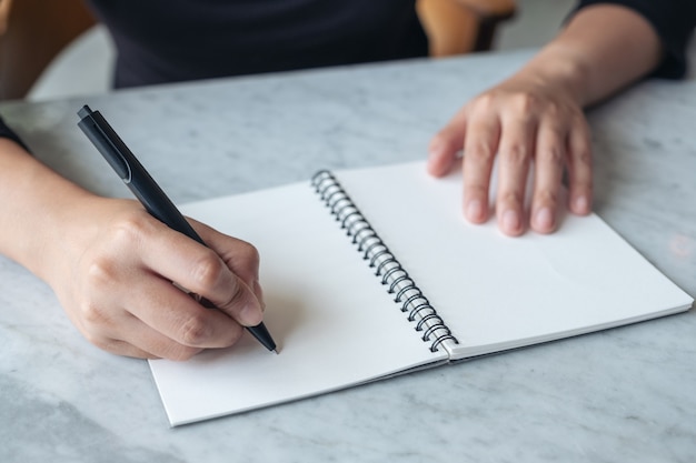 Sluit omhoog beeld van handen schrijvend op leeg notitieboekje op de lijst