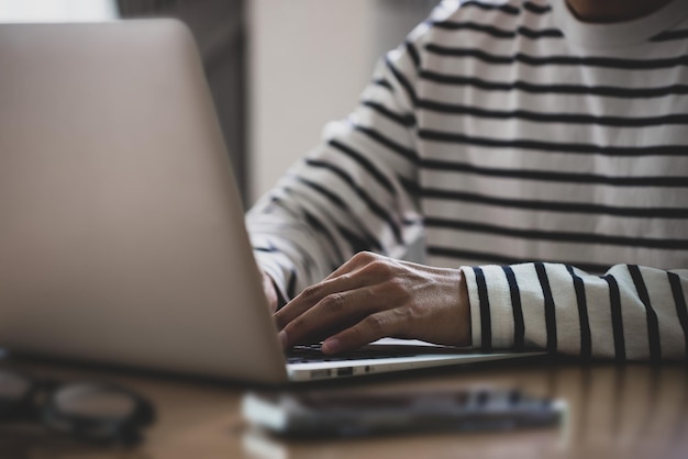 Sluit omhoog beeld van zijaanzicht van mannelijke handen die op laptop toetsenbord typen