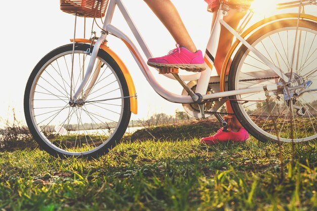 Sluit omhoog beenvrouw op fiets met zonsondergang bij park