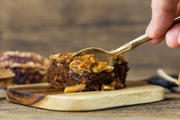 Sluit omhoog de cake van de de lepeltoffee van de staallepel op houten lijstmuur.