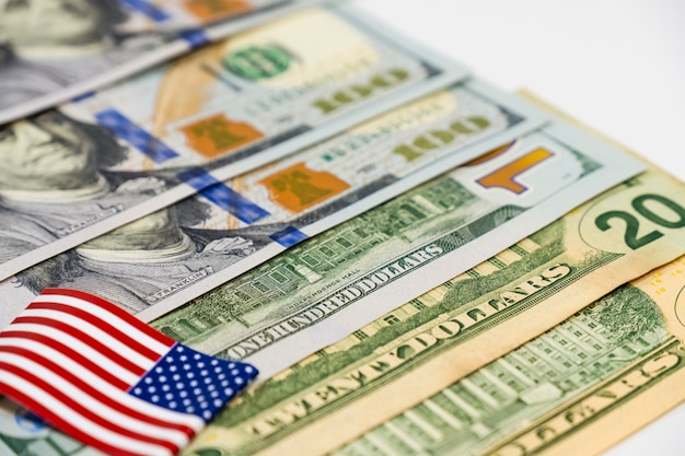 Sluit omhoog de dollarbankbiljetten van de VS en de vlag van de Verenigde Staten van Amerika op witte achtergrond.