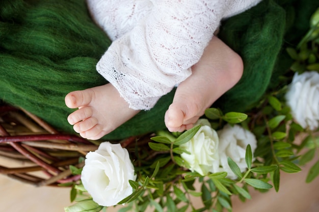 Sluit omhoog foto van pasgeboren babyvoeten op gebreide plaid en bloemen