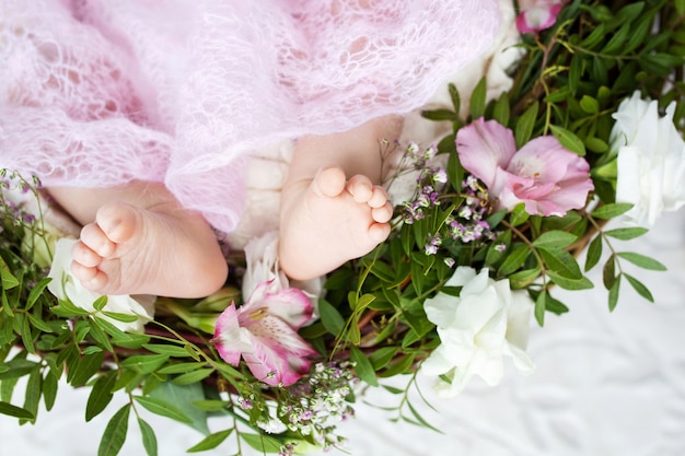 Sluit omhoog foto van pasgeboren babyvoeten op gebreide plaid en bloemen