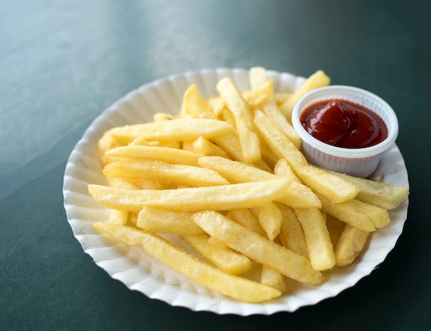 Sluit omhoog Frietenaardappels met ketchup op witte schotel.