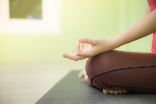 Sluit omhoog geschoten van de hand die van de vrouw meditatie in lotus doen stellen yoga op een zwarte mat.