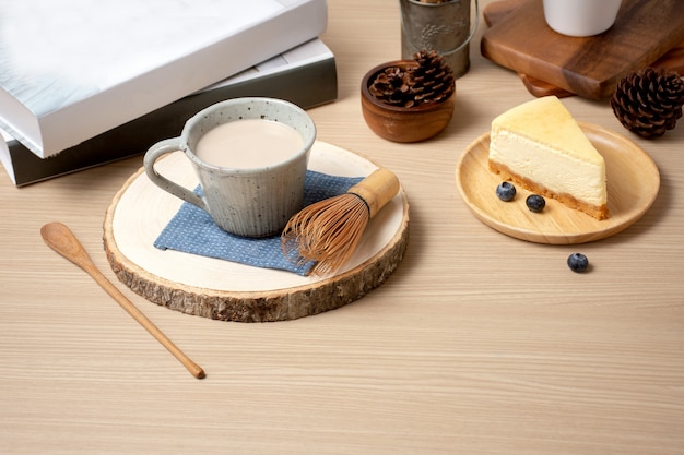 Foto sluit omhoog geschotene kop van koffie en cake met boek op lijst in de koffie van de koffiewinkel