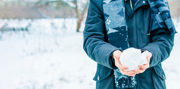 Sluit omhoog handen houdend sneeuw op een de winterdag in openlucht