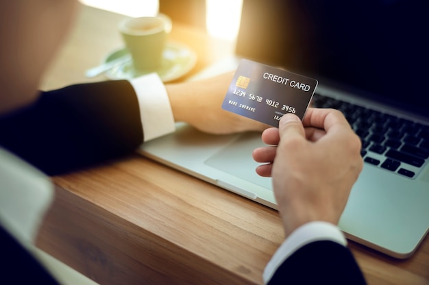 Sluit omhoog handen van de creditcard van de zakenmanholding en gebruikend labtop verrichtend online betaling. Online winkelen concept.