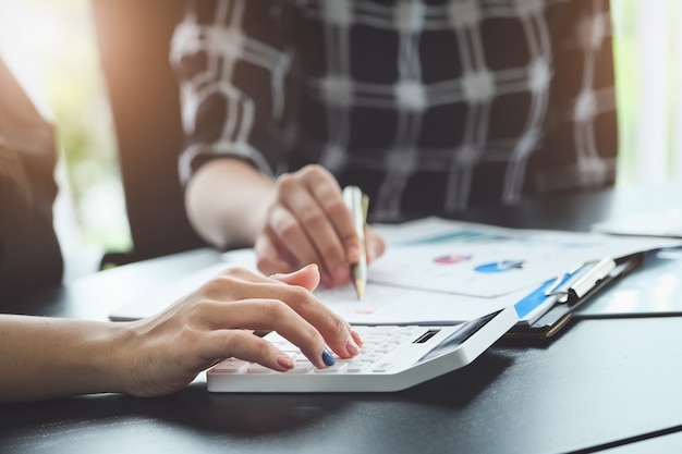 Sluit omhoog handvrouw die financiën doet en op bureau over kosten op kantoor berekenen.