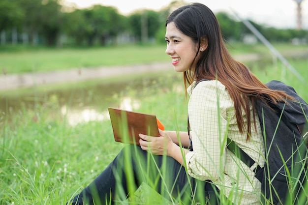 Sluit omhoog het Aziatische boek van de studentenvrouw alleen bij openluchtpark met concentraat