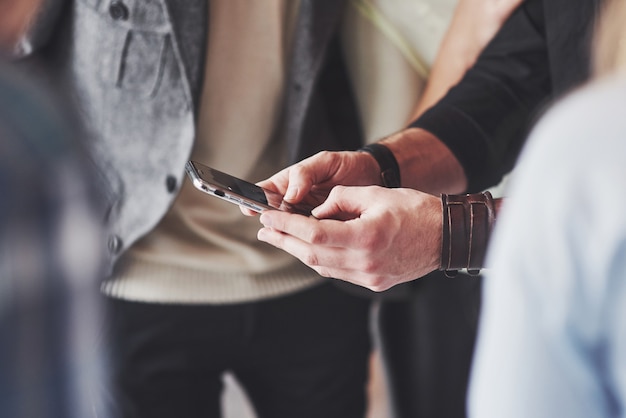 Sluit omhoog jonge vrienden die slimme telefoon bekijken terwijl het zitten in koffie