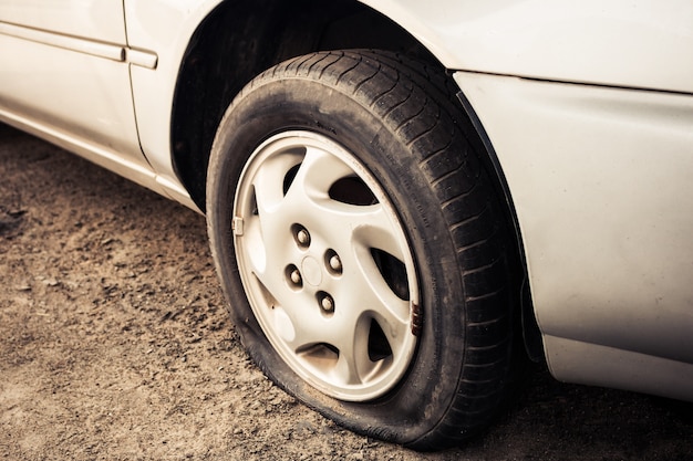 Sluit omhoog Lekke band en oude auto op de weg die op reparatie wachten