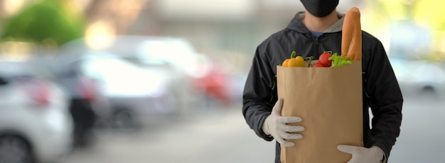 Sluit omhoog mening van de dienstmens van de voedsellevering die verse voedselzak houden