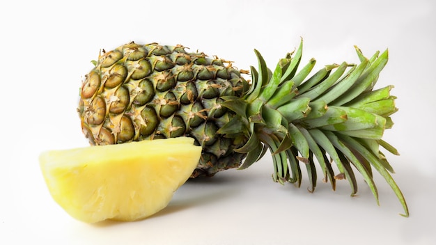 Sluit omhoog mening van gehele en gesneden rijpe geïsoleerde ananas