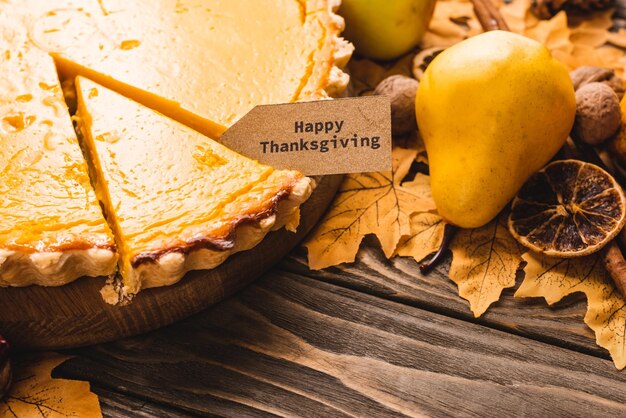 Foto sluit omhoog mening van herfstdecoratie en pompoenpastei met gelukkige dankzeggingskaart op bruin houten