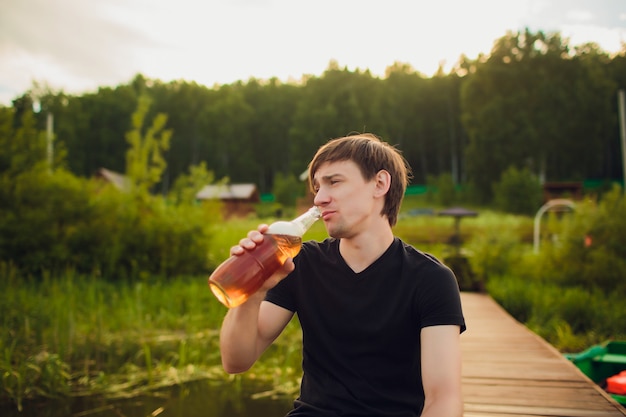 Sluit omhoog mens het drinken bier van glas bij openlucht dichtbij het zwembad. Alcohol en vrije tijd concept.