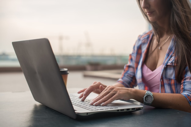 Sluit omhoog ontsproten van vrouwelijke handen typend op een laptop toetsenbord.