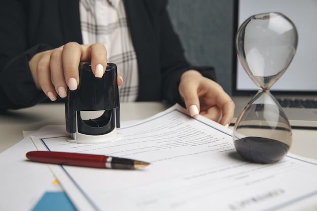 Sluit omhoog op de notarishand van de vrouw die het document stempelt.