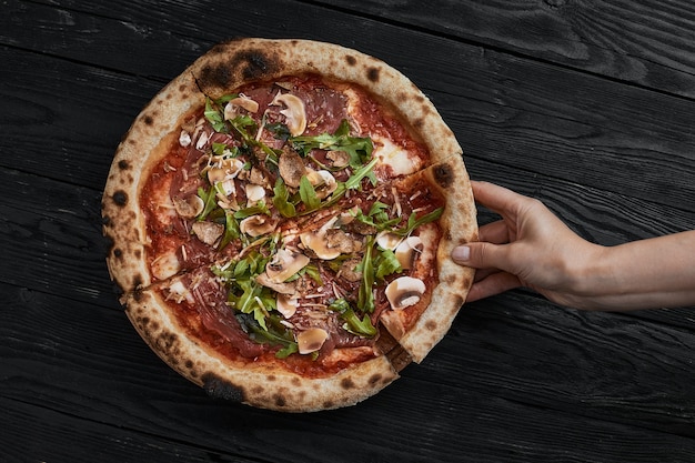 Sluit omhoog op heerlijke, versgebakken kleine pizza met gesmolten kaaschampignons en basilicum.