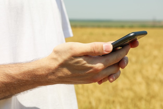 Sluit omhoog op mens met telefoon in gerstgebied