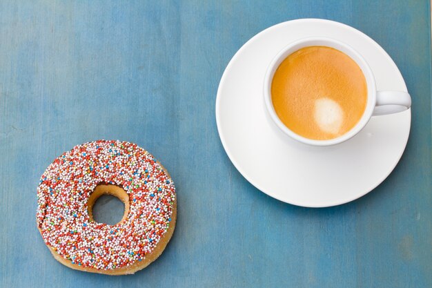 Sluit omhoog op verse donuts die naast koffiekop leggen