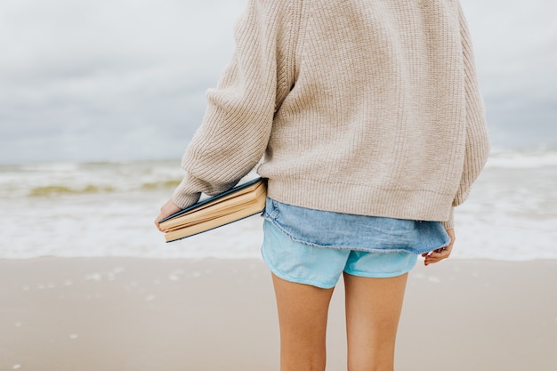 Sluit omhoog op vrouw dichtbij kust die een boek houdt