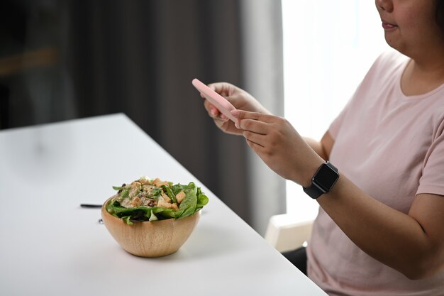 Sluit omhoog op vrouw die met behulp van slimme telefoon foto van salade nemen