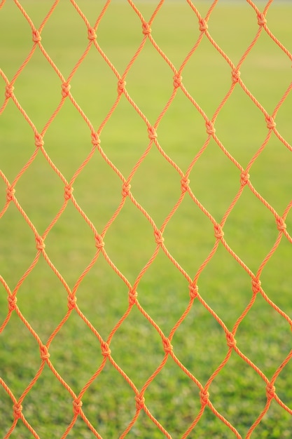 Sluit omhoog oranje voetbal netto op groene grasachtergrond