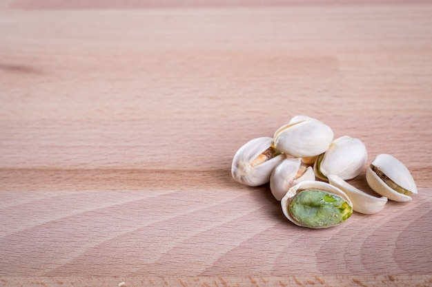 Sluit omhoog pistachenoten met shell op houten vloerachtergrond.