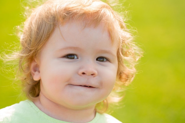 Sluit omhoog portret van een blonde baby. grappige kinderen gezicht in zomer natuurpark.