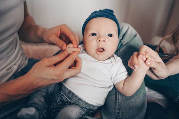 Sluit omhoog portret van gelukkige ouders die hun baby houden. Jonge gelukkige familie, moeder en vader spelen met schattige emotionele kleine pasgeboren kind zoon in de slaapkamer