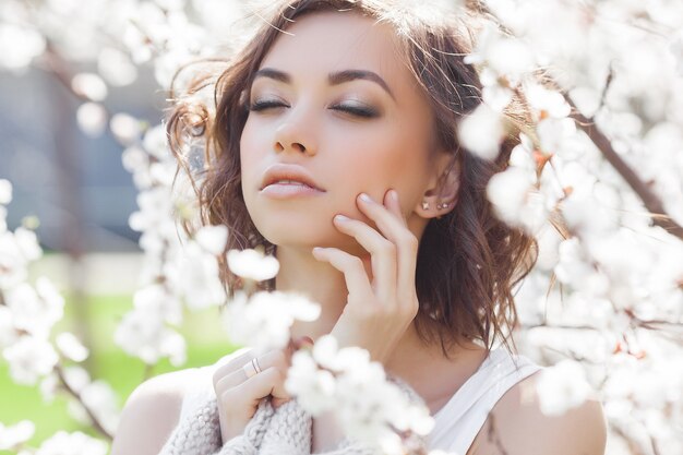 Sluit omhoog portret van jonge mooie vrouw op de lente. Aantrekkelijk jong meisje met bloemen. Lente make-up model.