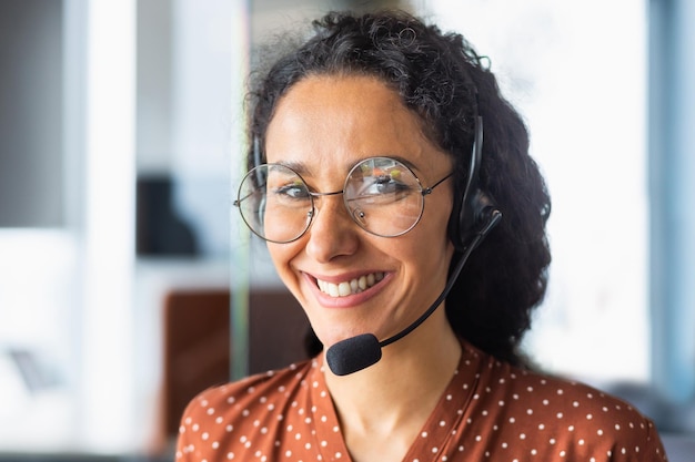 Sluit omhoog portret van Latijns-Amerikaanse vrouw binnen modern bureau met hoofdtelefoon voor videovraagvrouw