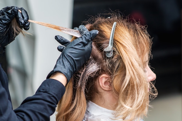 Sluit omhoog proces om het haar van de vrouw te verven bij schoonheidssalon.