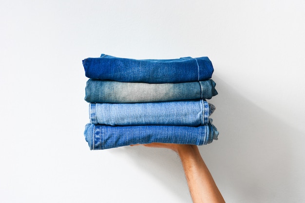 Sluit omhoog stapel gevouwen denimjeans op hand