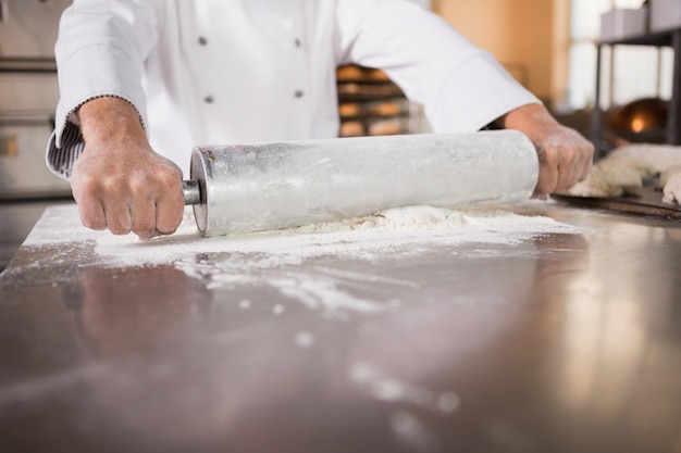 Sluit omhoog van bakker gebruikend een deegrol