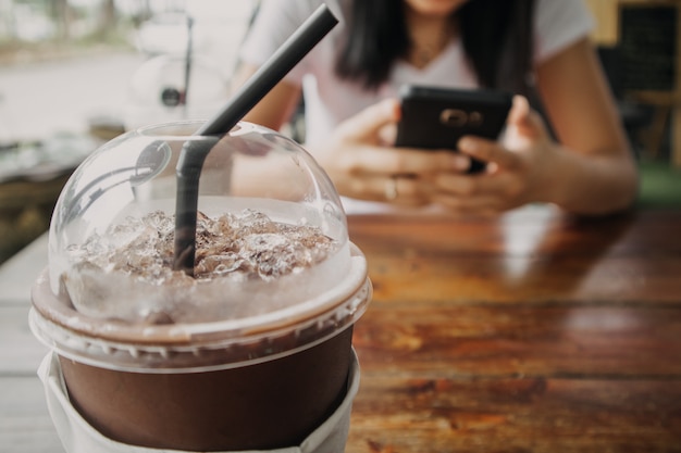 Sluit omhoog van bevroren koffie en cacaodrank in plastic kop op houten lijst.