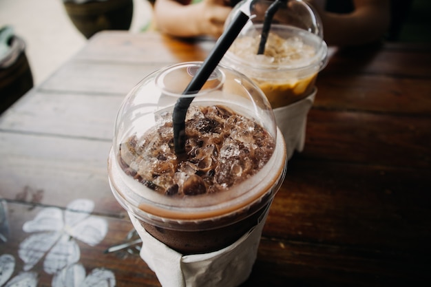 Sluit omhoog van bevroren koffie en cacaodrank in plastic kop op houten lijst.