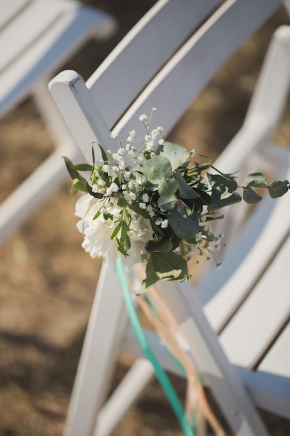 Foto sluit omhoog van bloem die op huwelijksstoel wordt verfraaid