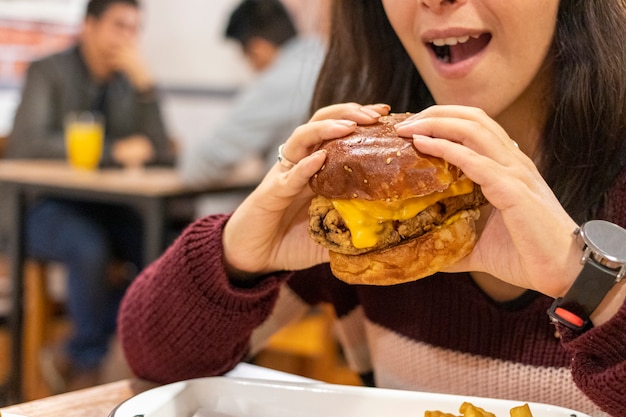 Sluit omhoog van cheeseburger met kaas met vrouw klaar om het te eten