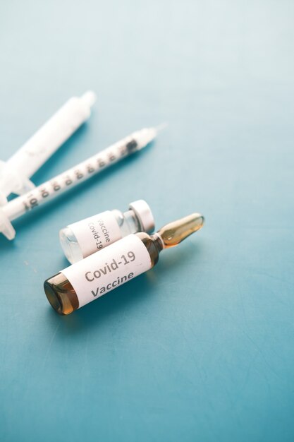 Sluit omhoog van coronavirusvaccin en spuit op groen bureau