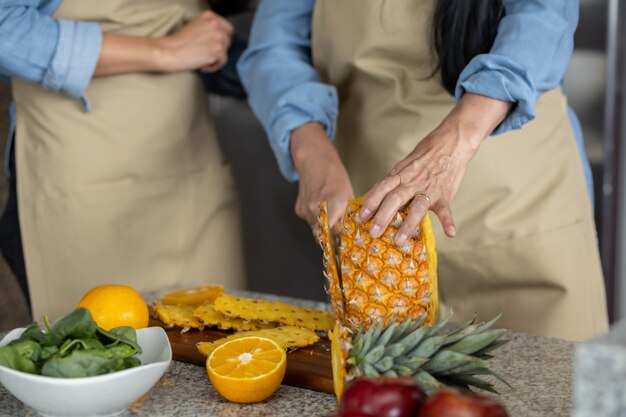 Sluit omhoog van de hand die van de vrouw een ananas snijdt