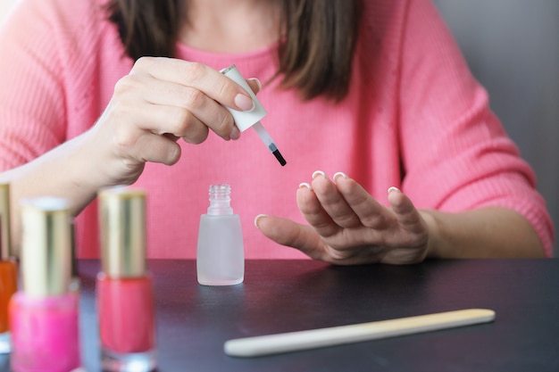 Sluit omhoog van de handen van een jonge vrouw die een manicurehuis maakt.