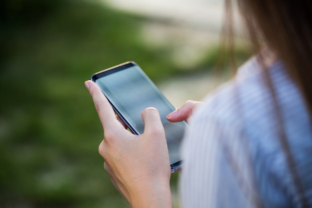 Sluit omhoog van de handen van vrouwen houdend celtelefoon met het lege scherm voor tekstbericht of promotieinhoud