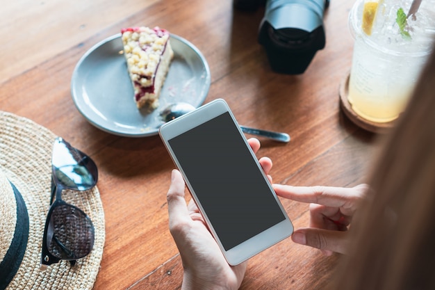 Sluit omhoog van de handen van vrouwen houdend mobiele telefoon in koffie.