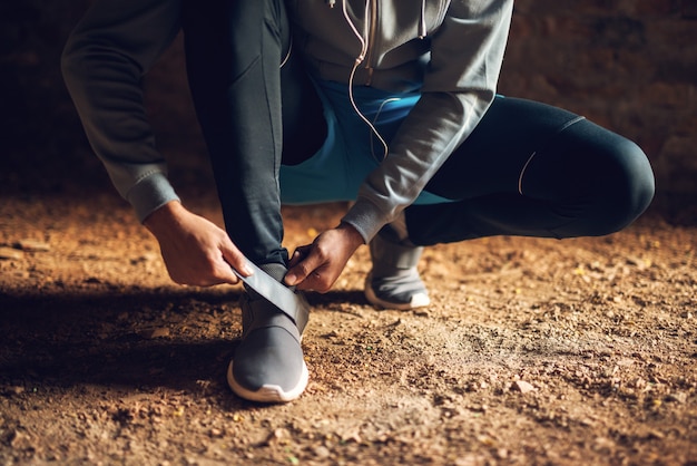 Sluit omhoog van de jonge actieve sportieve agentmens in sportkleding die zijn klittenbandschoen buiten binden.