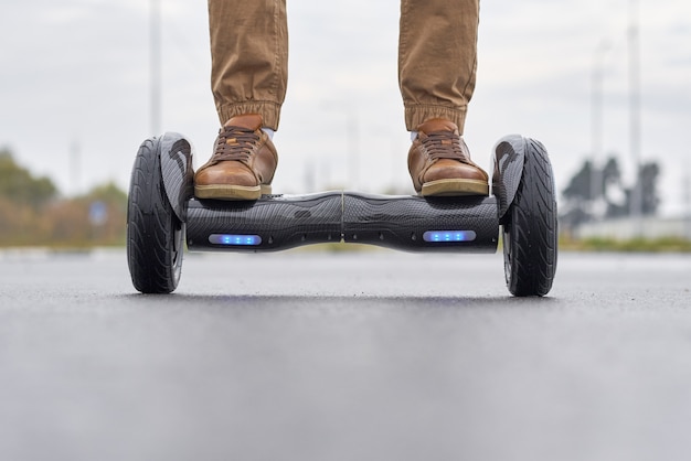 Sluit omhoog van de mens gebruikend hoverboard op asfaltweg.