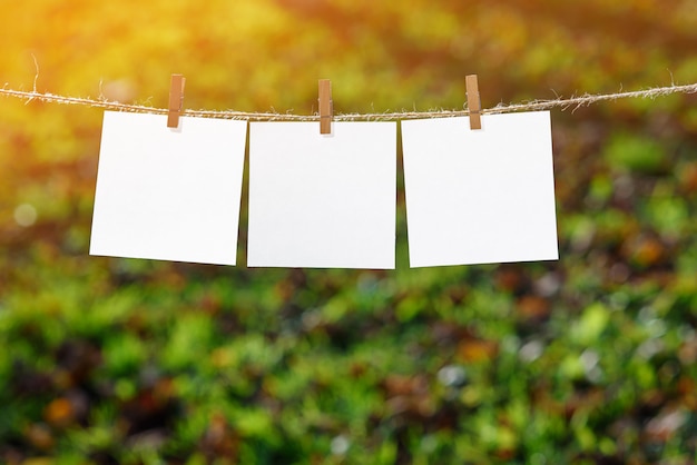 Sluit omhoog van drie witte notadocumenten die door houten wasknijpers worden gehangen