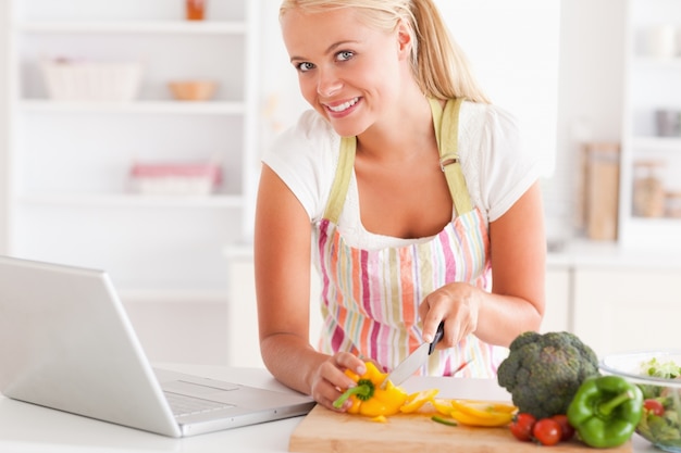 Sluit omhoog van een blonde vrouw gebruikend laptop om te koken