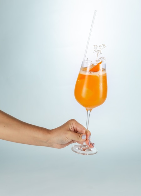 Sluit omhoog van een hand houdend een glas cocktail van Singapore op wit met exemplaarruimte.